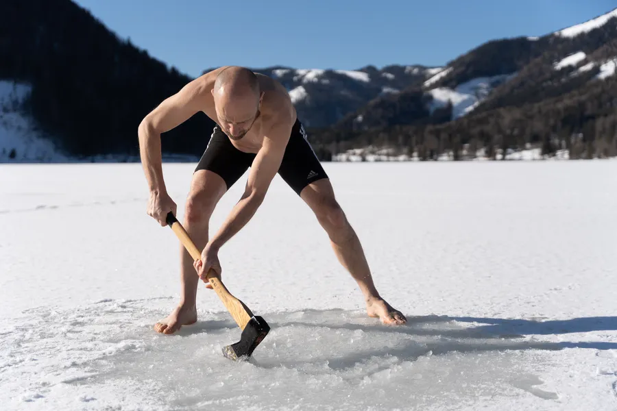 Mentaltrainer Marcus Bernhardt hackt mit einer Axt ein Loch in den zugefrorenen Erlaufsee zur Vorbereitung auf das Eisba