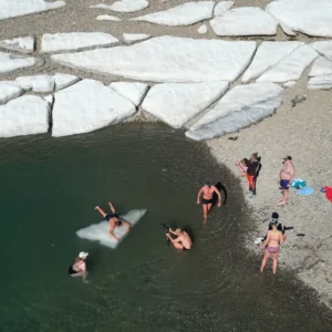 Drohnenaufnahme einer Gruppe beim Eisschwimmen Retreat Österreich am Mölltaler Gletscher mit Eisschollen im Wasser
