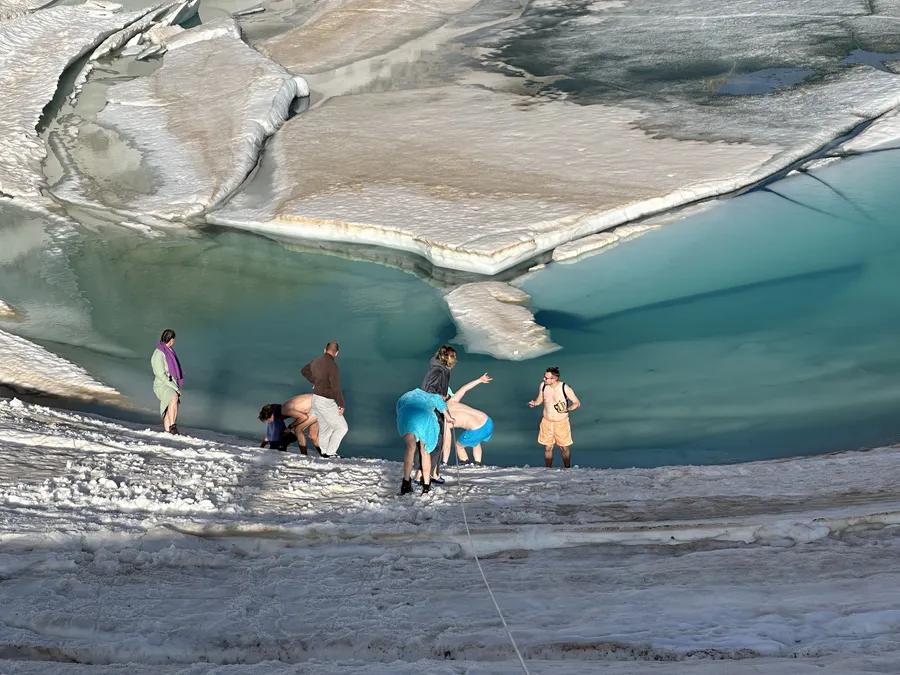 Gruppe beim Eisschwimmen Retreat Österreich am Gletschersee mit großen Eisschollen und türkisem Wasser