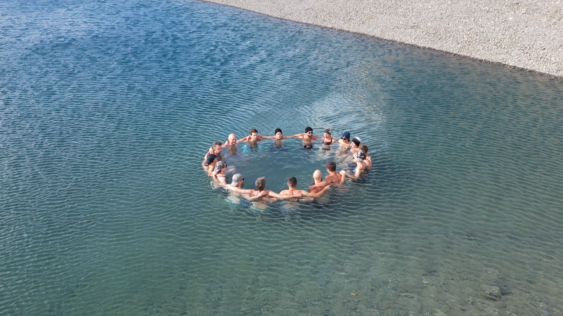 Drohnenaufnahme einer Gruppe beim Eisschwimmen Retreat Österreich, die im Kreis im kalten Wasser steht – Kältetraining a
