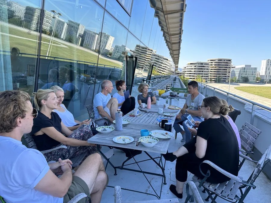 Teilnehmer beim Mittagessen während Kältetraining Wien Workshop kleine Gruppe auf einer Terrasse mit Blick auf die Rennb