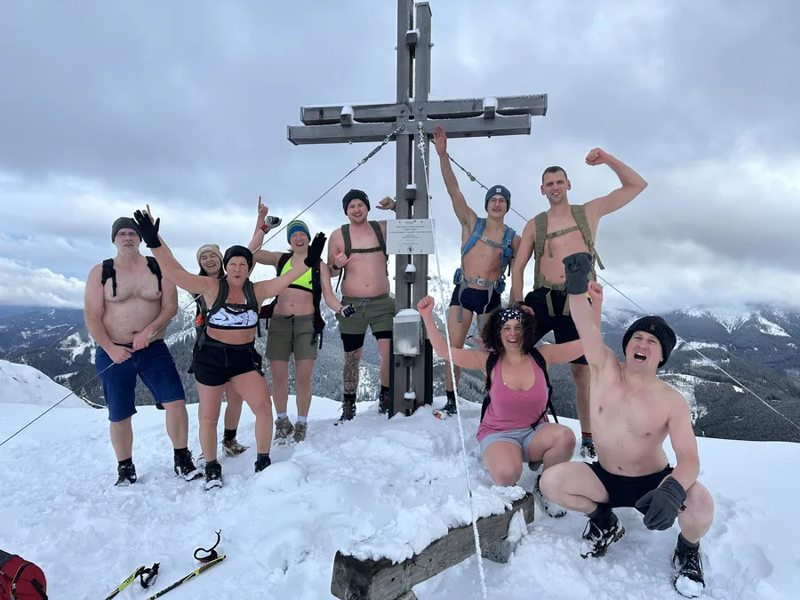 Gruppe feiert Gipfelsieg in Badekleidung beim Mentaltraining Retreat Österreich und Kältetraining in den Bergen
