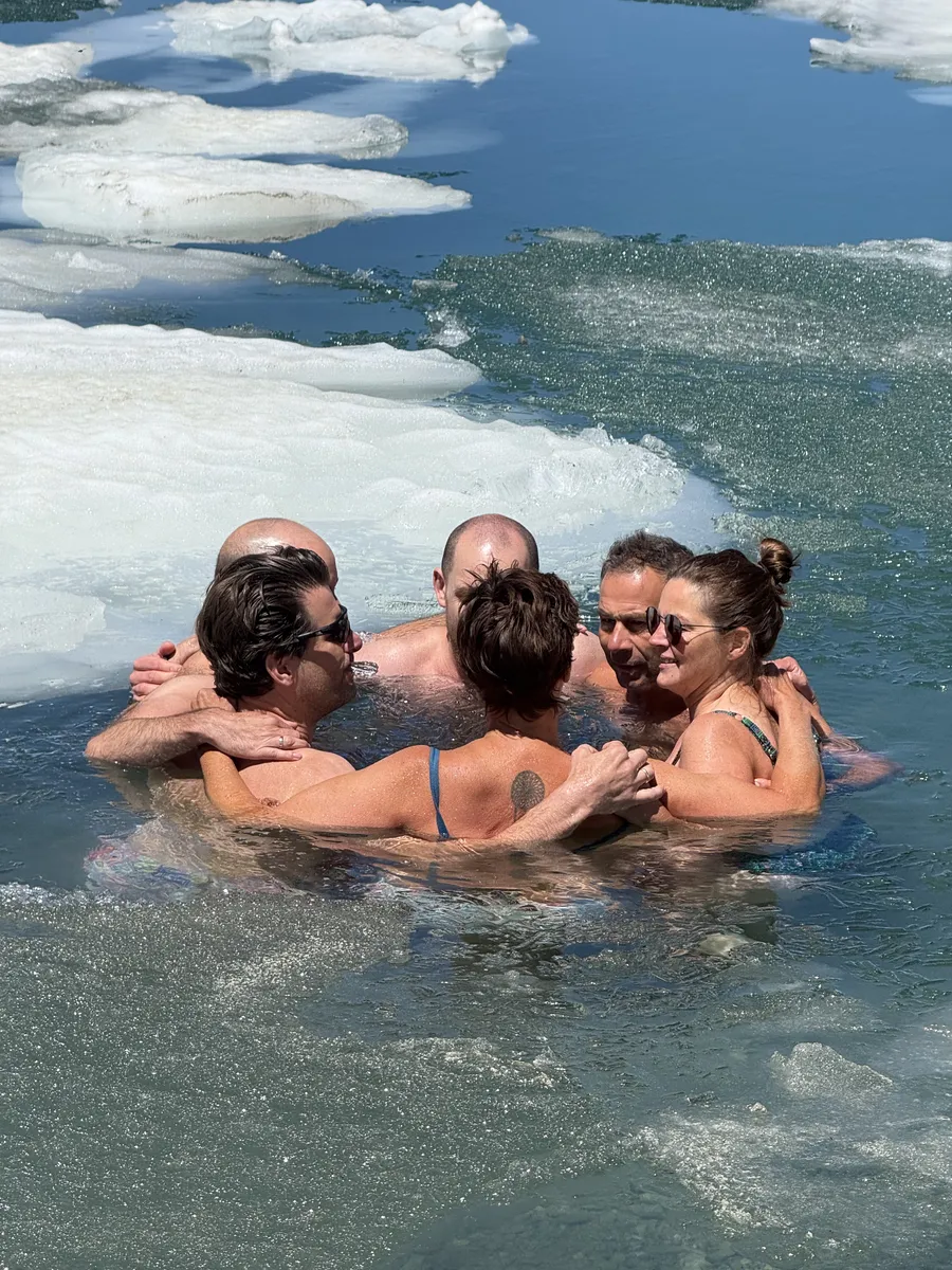 Gruppe umarmt sich im Eiswasser beim Eisschwimmen Retreat Österreich und Kältetraining am Gletscher