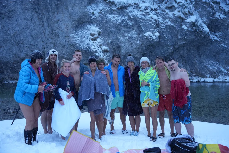 Teilnehmer beim Kältetraining und Eisschwimmen Retreat Steiermark stehen glücklich im Schnee am Flussufer