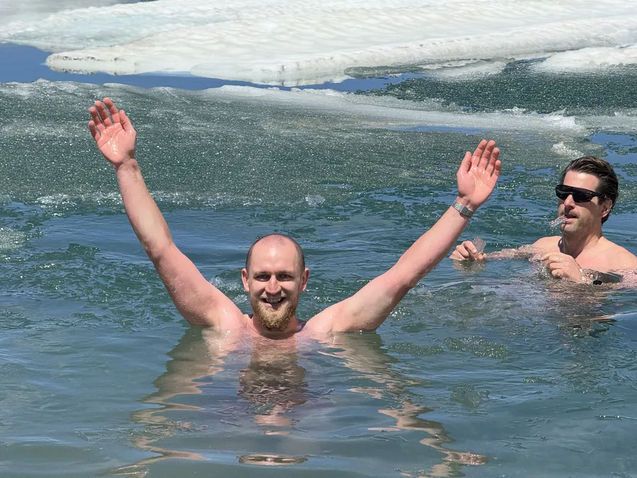 Jubel beim Eisschwimmen Retreat in Österreich am Gletschersee - medium Mann jubelt mit erhobenen Armen beim Eisschwimmen Retreat Österreich im kalten Gletscherwasser
