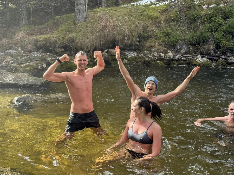 Gruppe jubelt beim Eisbaden und Kältetraining in einem kalten Fluss während eines Mentaltraining Retreats in Österreich.