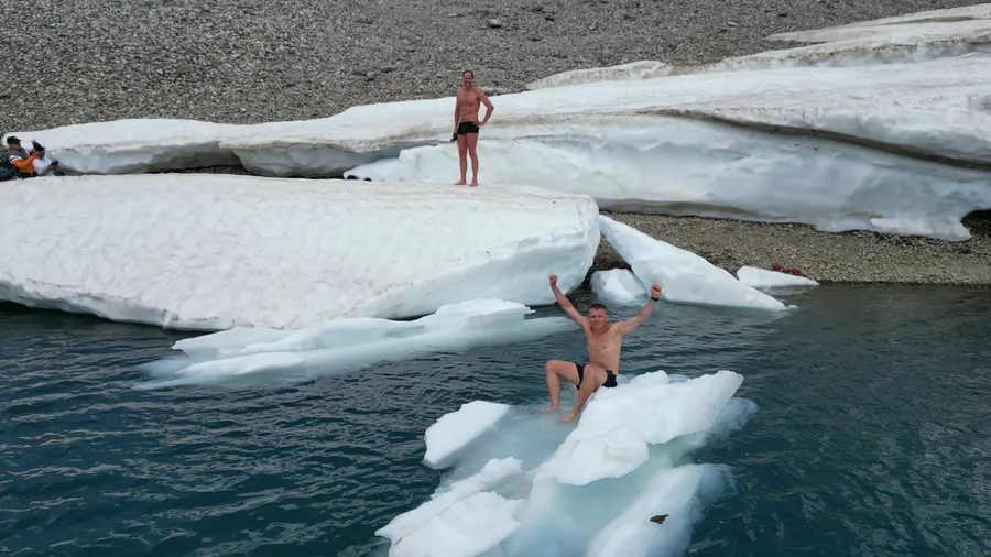 Mann jubelt auf Eisscholle beim Eisschwimmen Retreat Österreich und Kältetraining am Gletscher