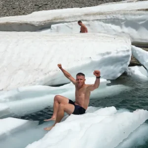 Teilnehmer beim Eisschwimmen Retreat Österreich sitzt jubelnd auf einer Eisscholle beim Kältetraining am Gletscher