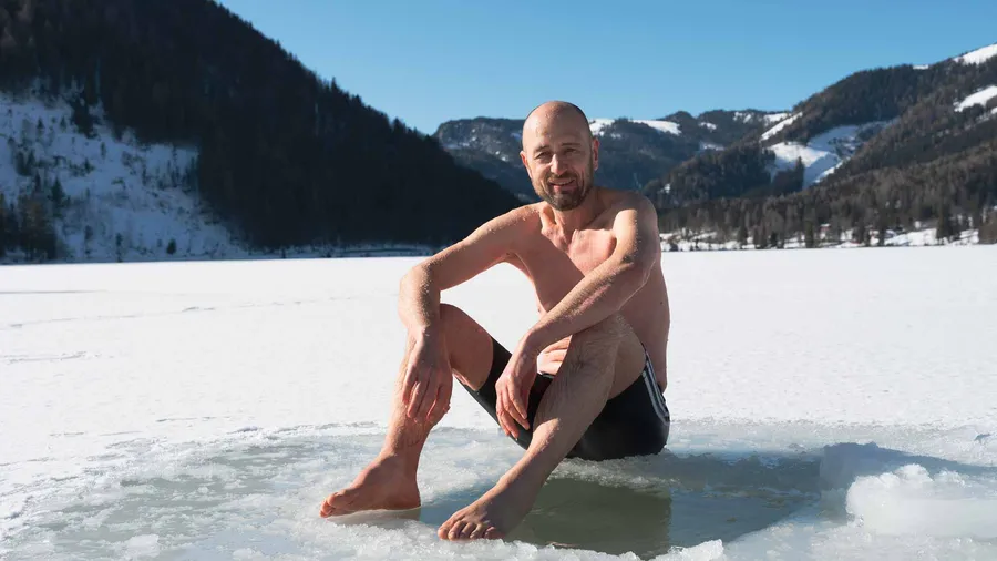 Eisbaden Coach Österreich Marcus Bernhardt sitzt entspannt am Rand eines Eislochs am zugefrorenen Erlaufsee