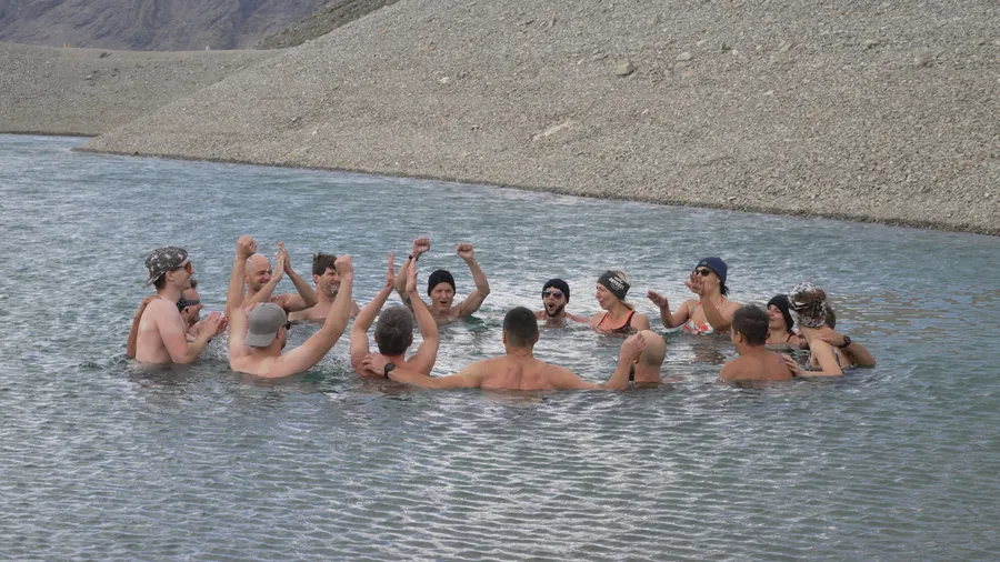 Gruppe feiert im Kreis im kalten Wasser beim Eisschwimmen Retreat Österreich und Kältetraining am Gletscher